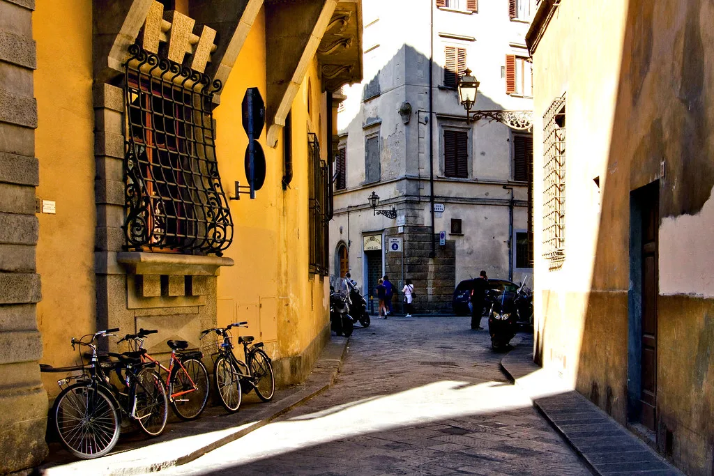 Narrow Florence old-town street with bicycles parked against ochre walls in a limited-traffic zone