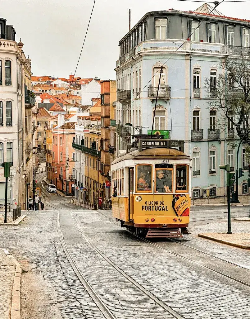 The historic yellow Tram 28 climbing a narrow cobbled street in the Alfama district of Lisbon