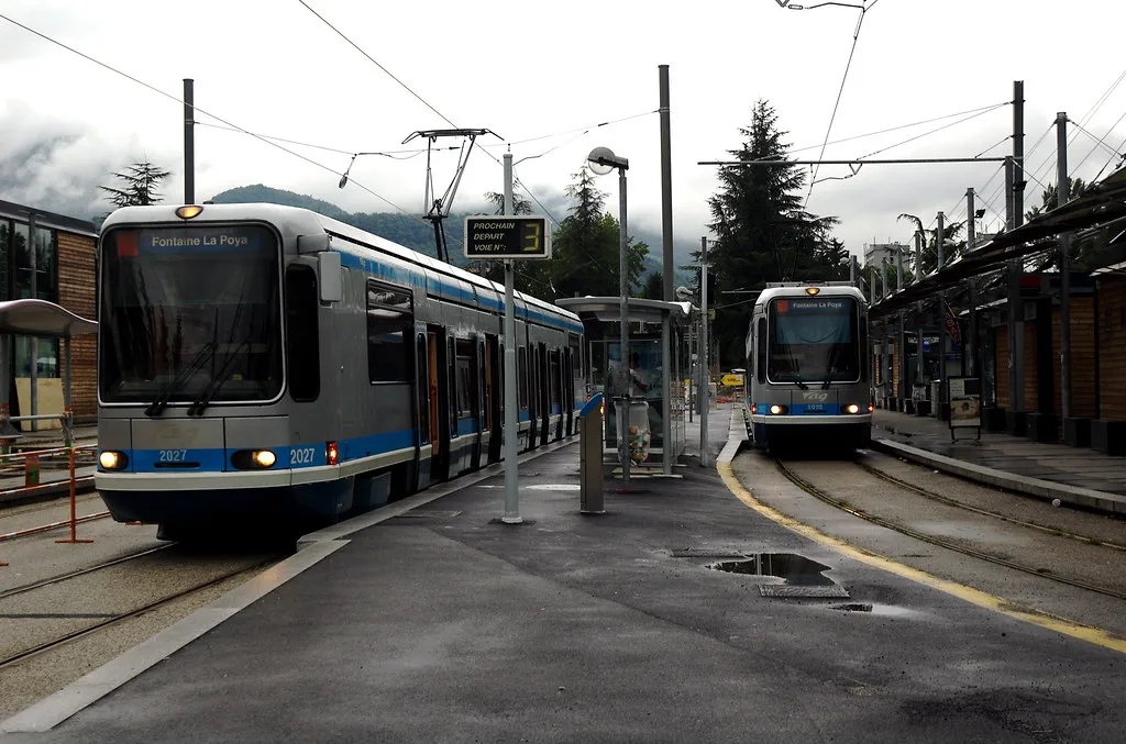 A blue M TAG tram running through a street in central Grenoble