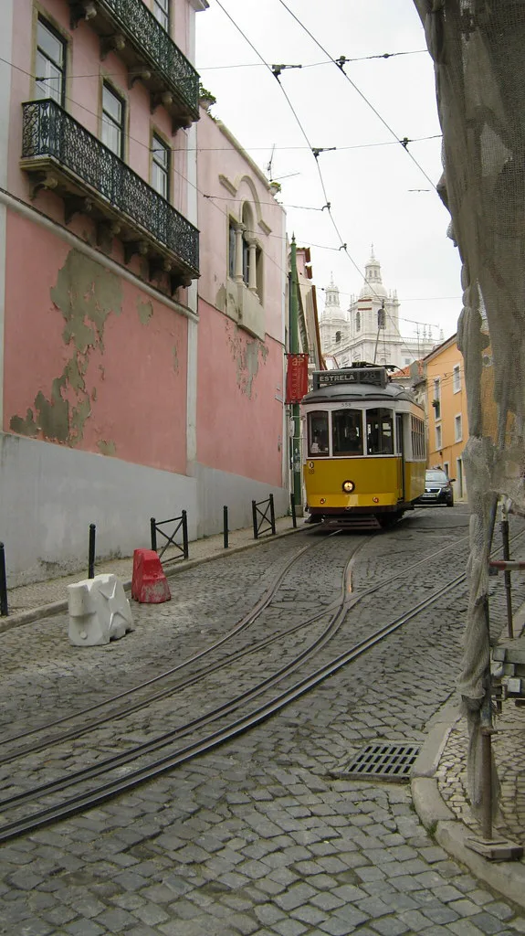 A vintage Lisbon tram climbing a narrow Alfama street