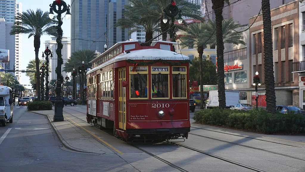 A historic green New Orleans streetcar running along its tracks