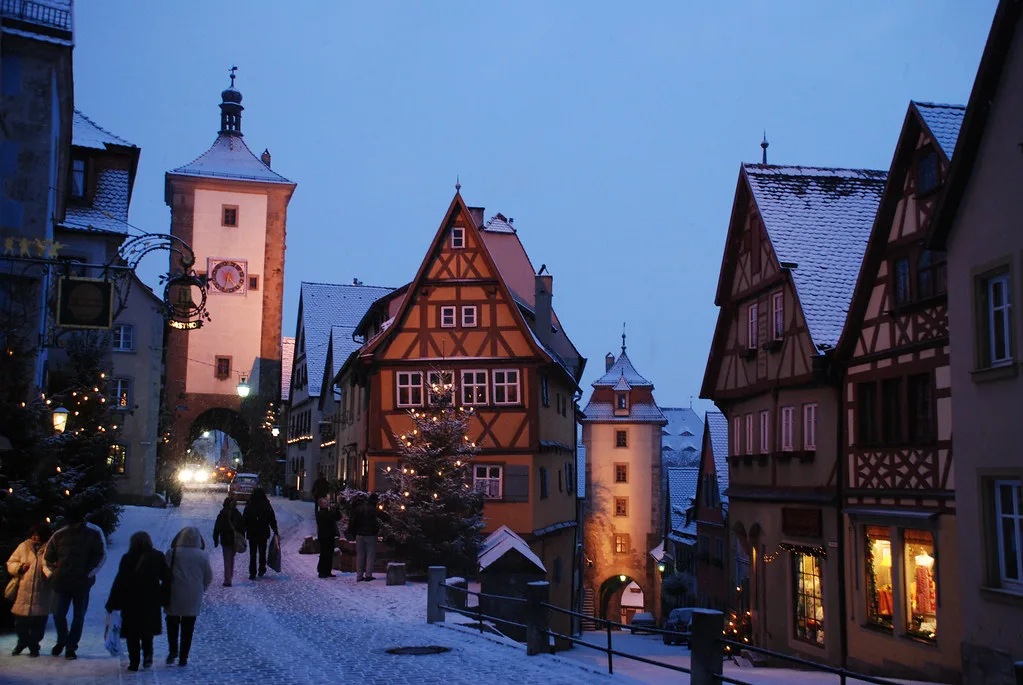 Festive wooden stalls and crowds at the Rothenburg ob der Tauber Christmas market at dusk